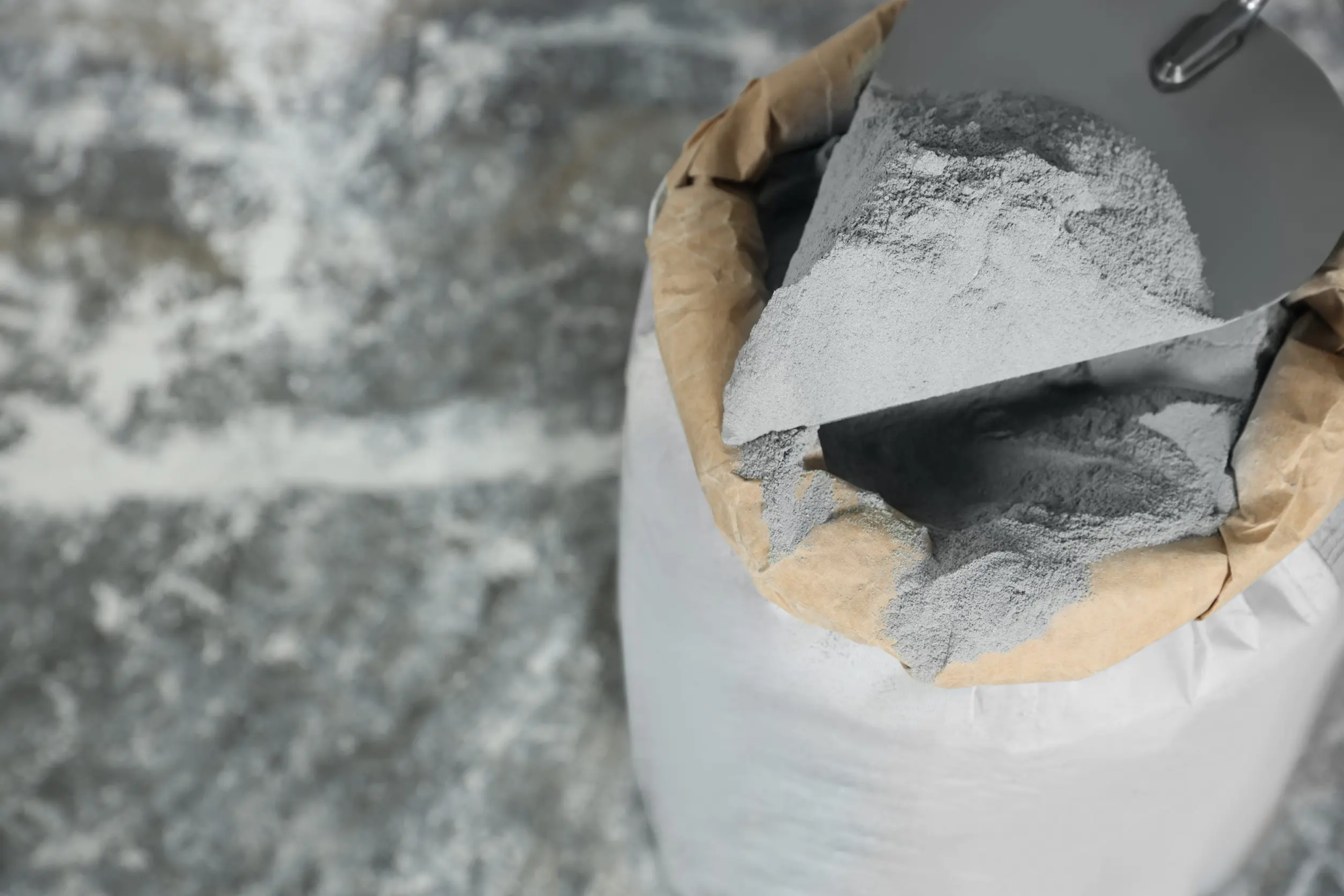 An open bag of cement powder with a trowel scooping up some of its contents for you to see
